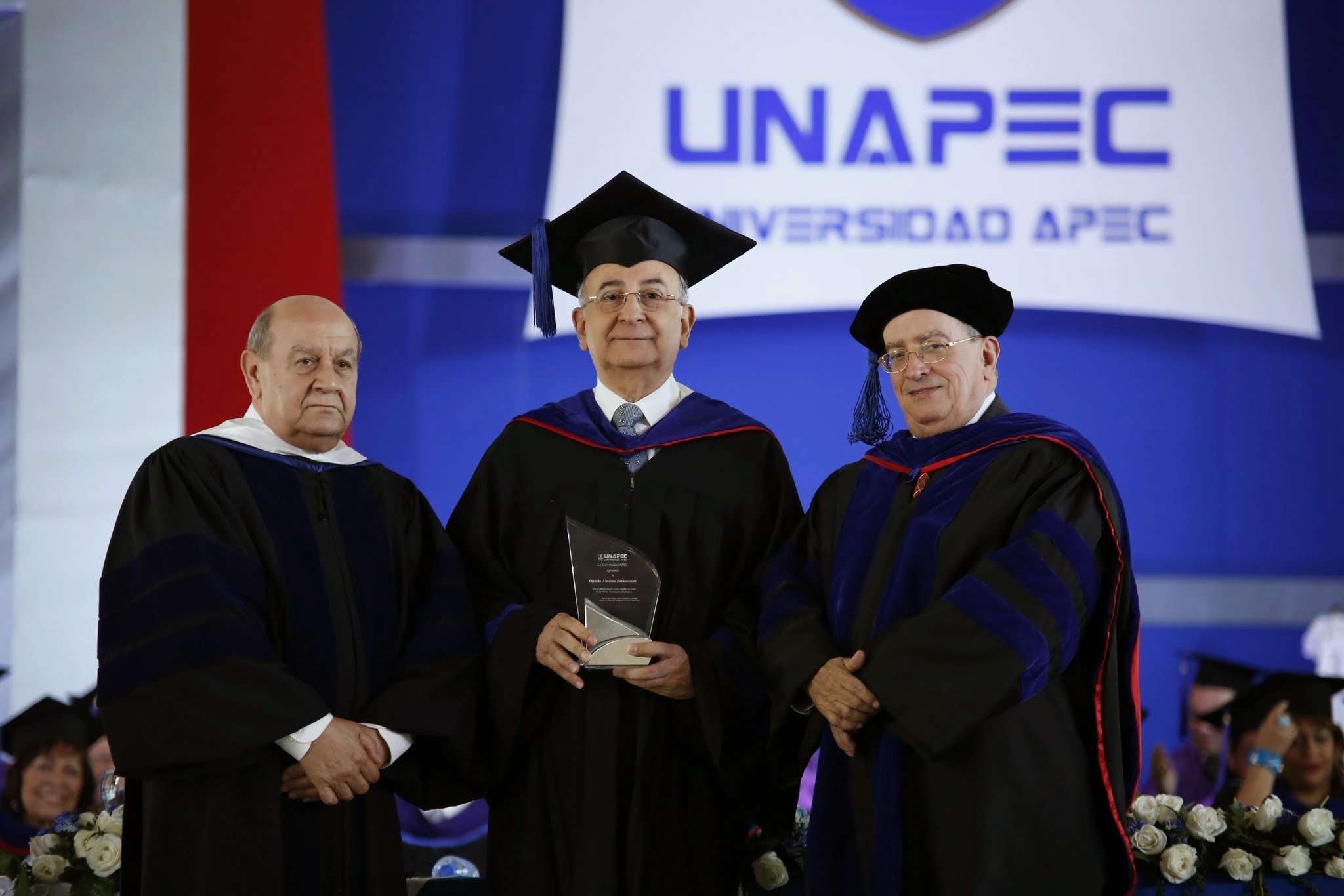 Franklyn Holguín Haché, Presidente de APEC, junto a Radhamés Mejía, Rector de UNAPEC mientras entregaban placa de reconocimiento a Opinio Álvarez Betancourt