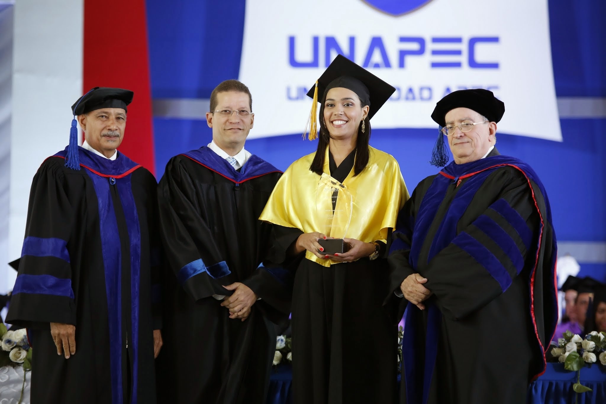 Raquel Blondet de León, egresada de Administración de Empresas, con el índice académico más alto de la ceremonia, mientras recibía el reconocimiento por su desempeño, de parte de las autoridades de UNAPEC
