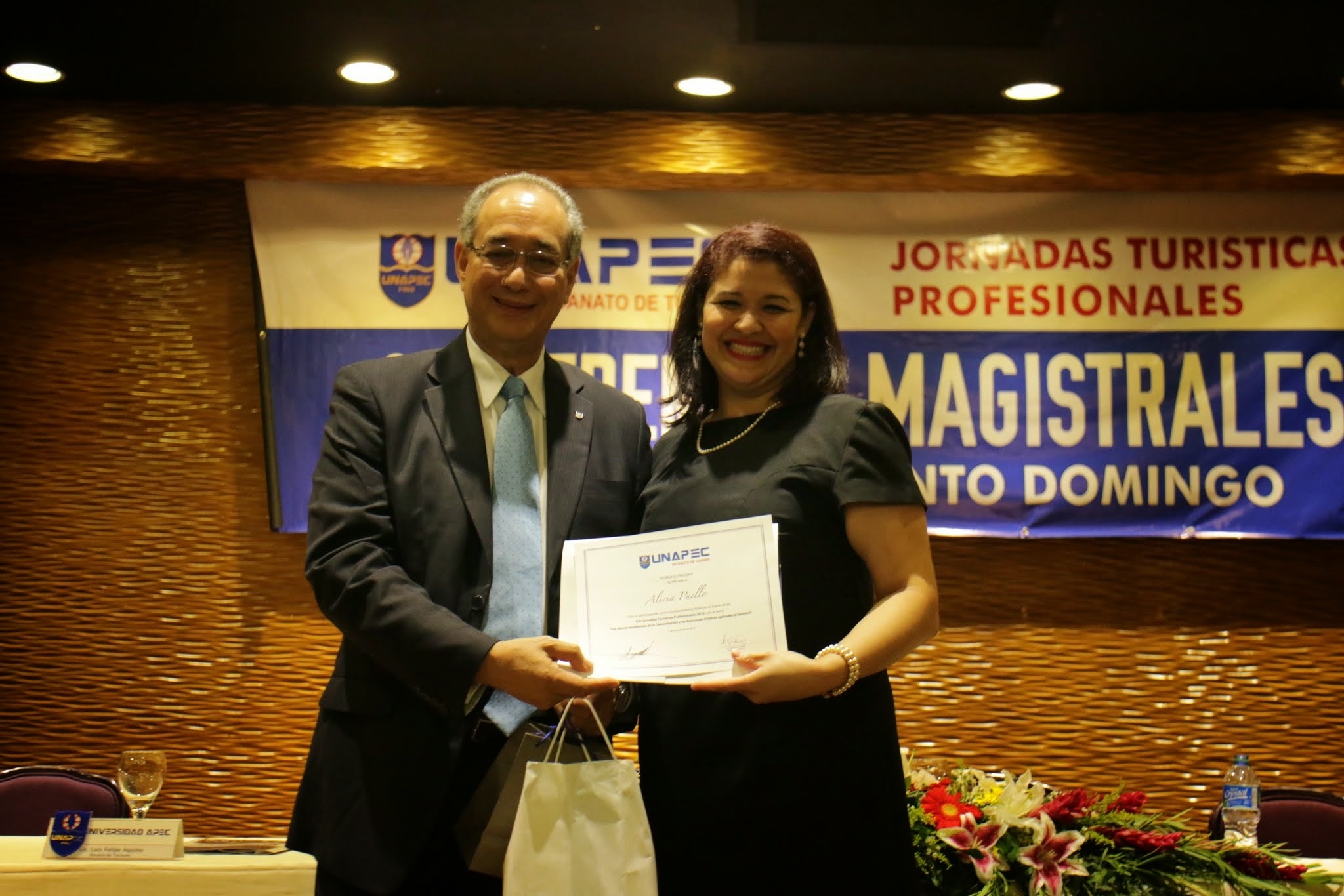 5.	Lic. Alicia Puello, Gerente de Comunicaciones del Banco BHD León, recibiendo reconocimiento de participación de manos de Luis Felipe Aquino, decano de Turismo.