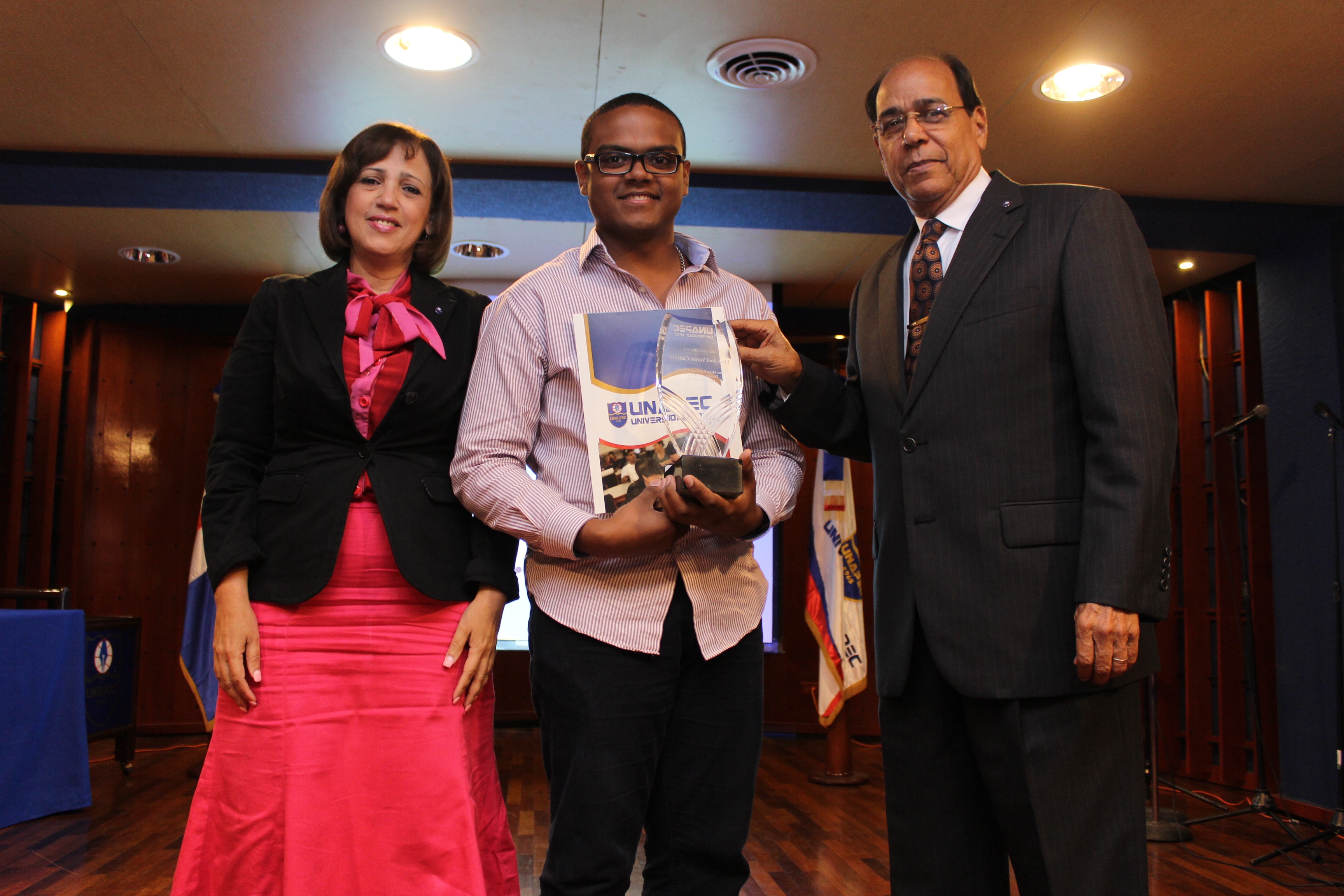Estudiante Elvis Joel Yunes Cabrera recibiendo reconocimiento de manos de Aida Roca y Pedro Antonio Eduardo.