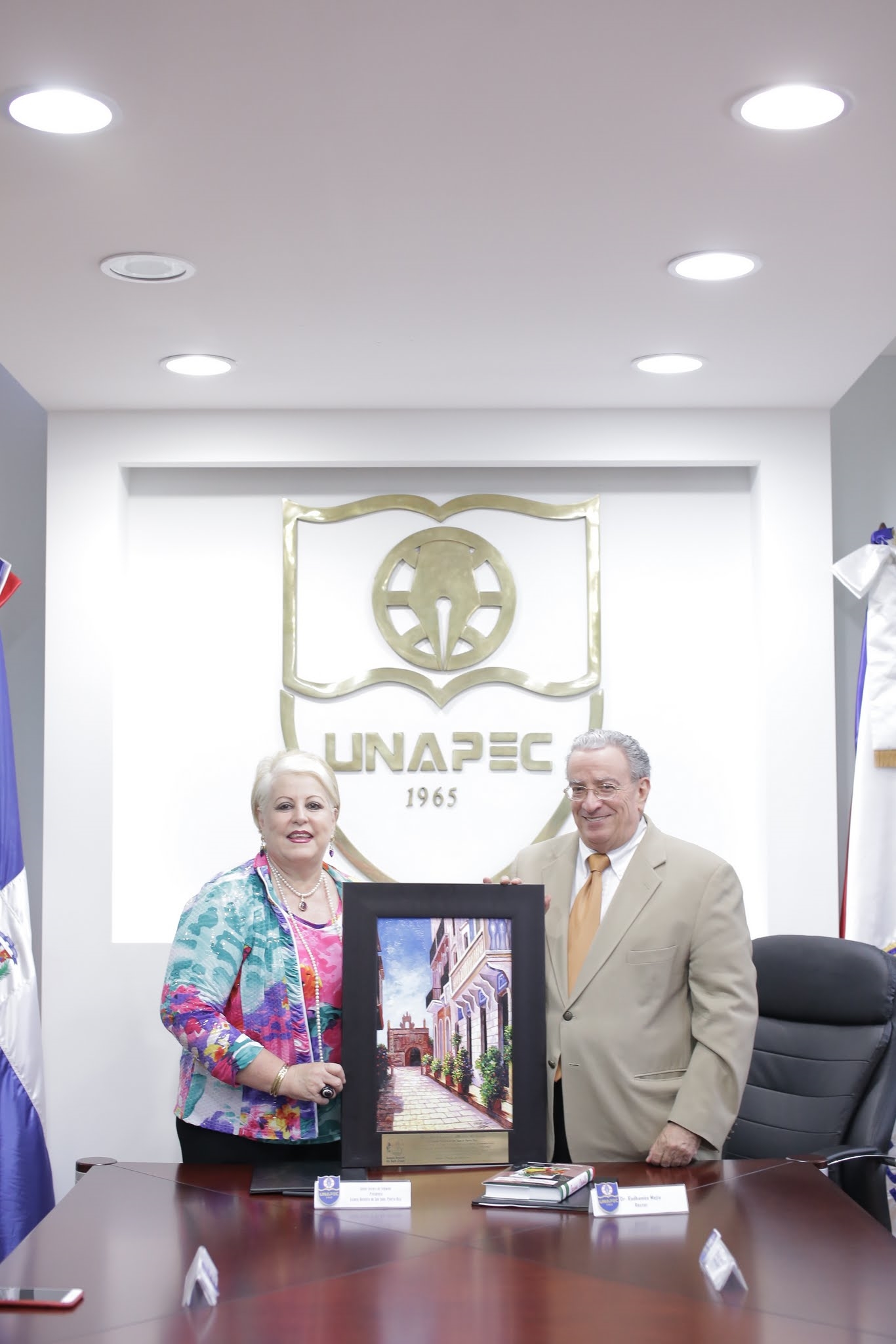 El Dr. Radhamés Mejía recibió de manos de la Dra. Sylvia Cestero de Seymour un cuadro de souvenir que representa el lugar más emblemático de San Juan, Puerto Rico.